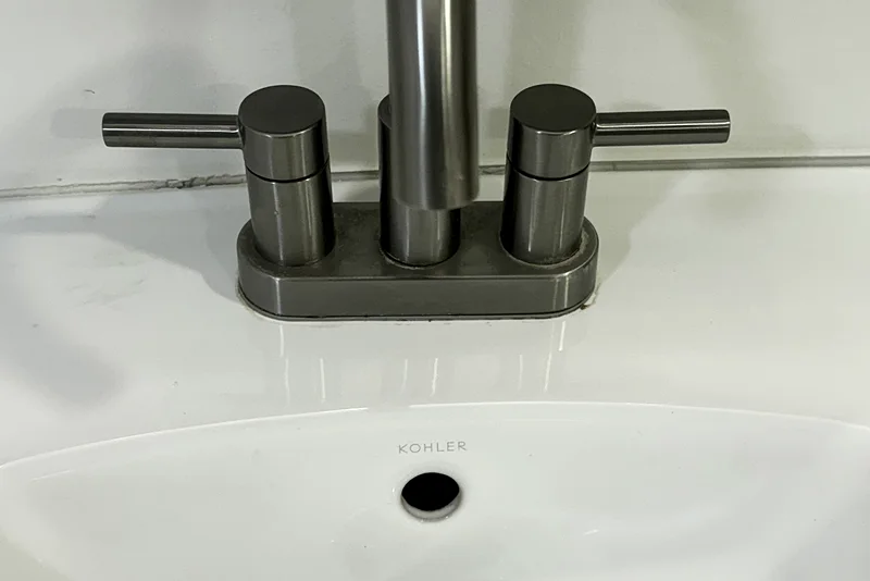 The same brushed-nickel faucet after cleaning: gleaming metal on a clear, wiped-down counter