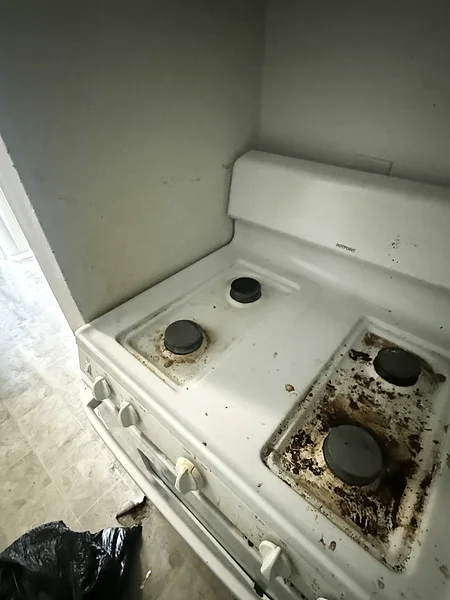 A white gas range before cleaning: burnt-on grease across the cooktop and dirty drip pans