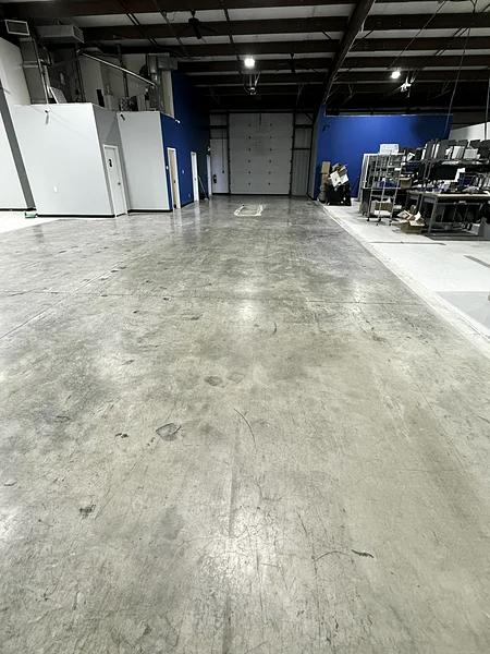 A commercial warehouse concrete floor before cleaning: scuffed, dull and covered in dust