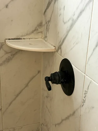 The same shower valve after cleaning: polished chrome and a clean corner shelf