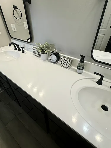 A double vanity with black faucets, cleaned and styled after service