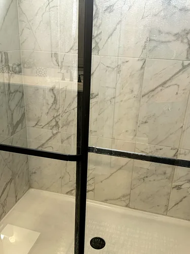 A detail of the marble shower glass, cleaned clear of water spotting