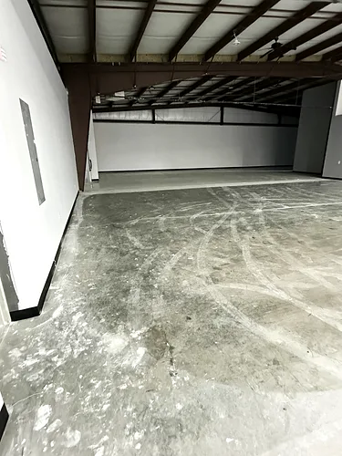 Dull, scuffed warehouse concrete before the crew starts