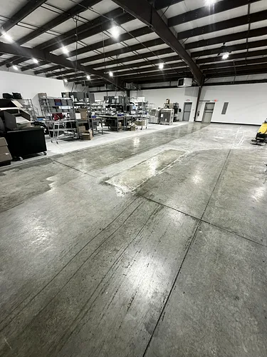 Worn warehouse floor edge and baseboard covered in dust, before cleaning