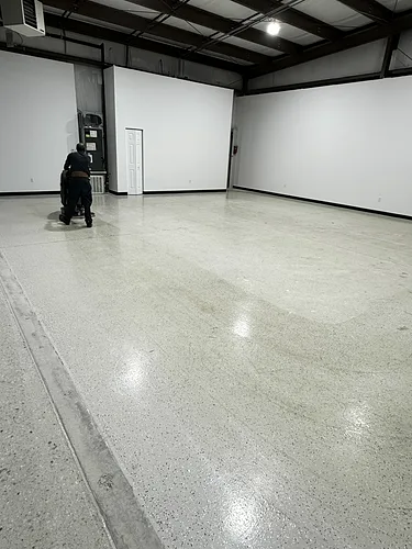 The floor scrubber mid-pass, leaving a clean wet lane behind it