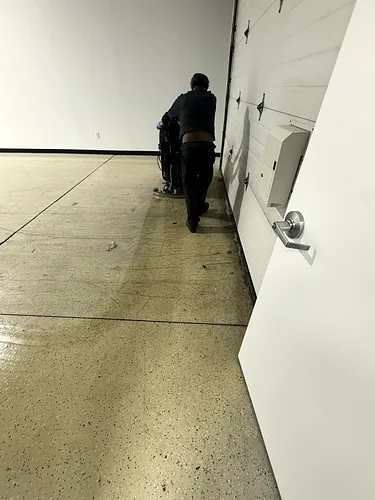 A crew member steering the scrubber along the warehouse aisle