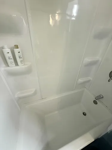 A white shower stall scrubbed clean in a rental bathroom