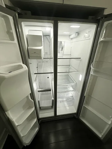 An emptied and wiped-out refrigerator, door open, after a rental turnover