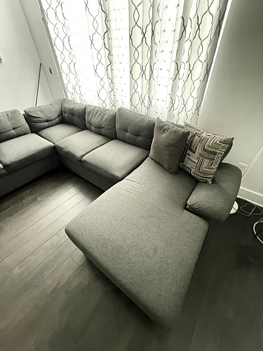 A grey sectional sofa vacuumed and straightened in a cleaned rental living room