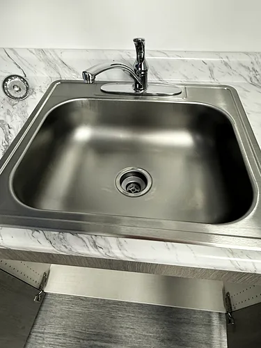 A polished stainless-steel kitchenette sink in an office break room